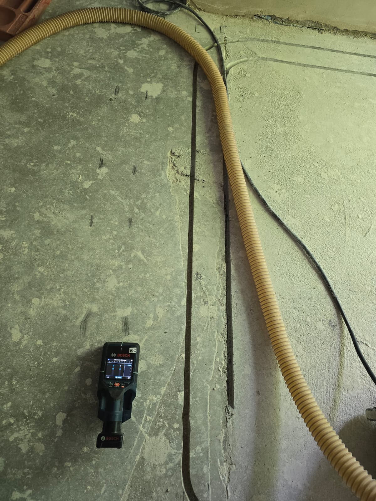 Bosch Ortungsgerät am Boden neben Leerrohr und markierten Leitungen im Anbau
